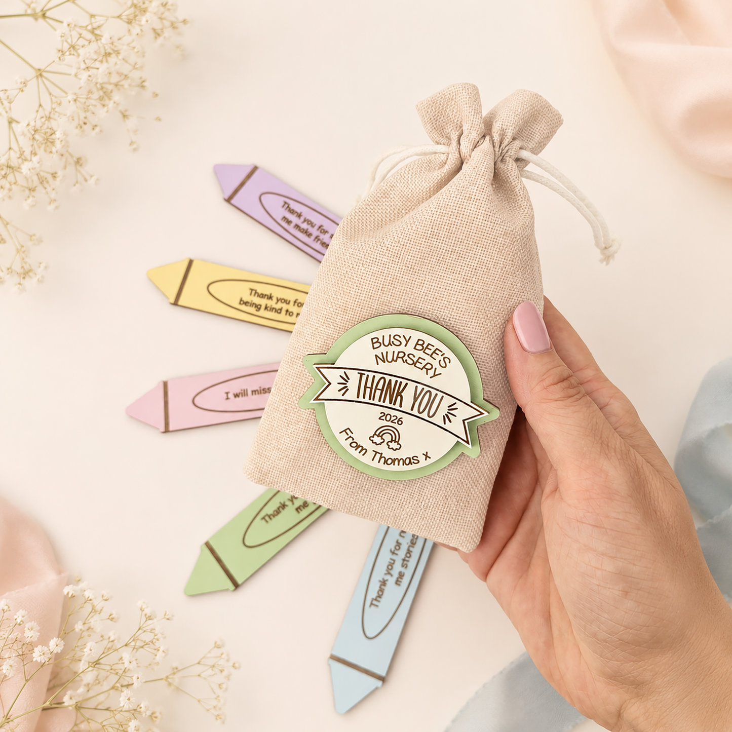 Personalised nursery thank you gift bag held by hand with colourful crayon tokens